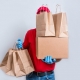 Symbol für Coronakrise im Einzelhandel - Zusteller liefert Ware und versteckt sich dahinter